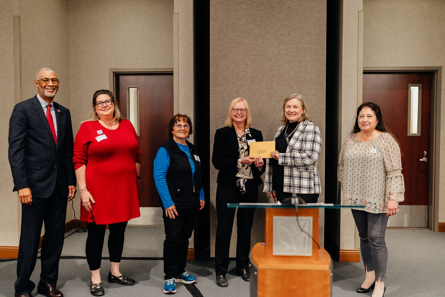 Two people holding envelope, flanked by four others